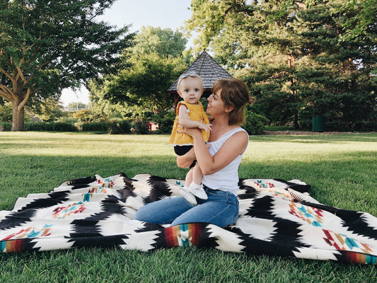 Child Sitting On A Blanket With Black And Beige Geometric Pattern By Bella Aura