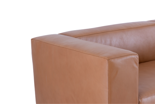 A detailed view of the square armrest and cushion joint of the Aaran leather sofa, emphasizing the premium upholstery.