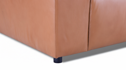 A close-up of the corner of the Aaran sofa, highlighting the smooth top grain leather, tonal stitching, and short black legs.