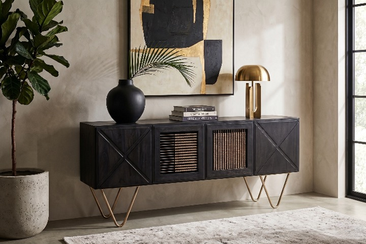 The black Aurelia Sideboard used as a statement console in a minimalist modern living room, styled with a brass lamp, palm vase, and Fiddle Leaf plant.