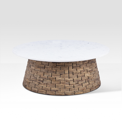 The Charme Coffee Table styled in a sunlit coastal living room, featuring a white marble top and a handwoven water hyacinth drum base.