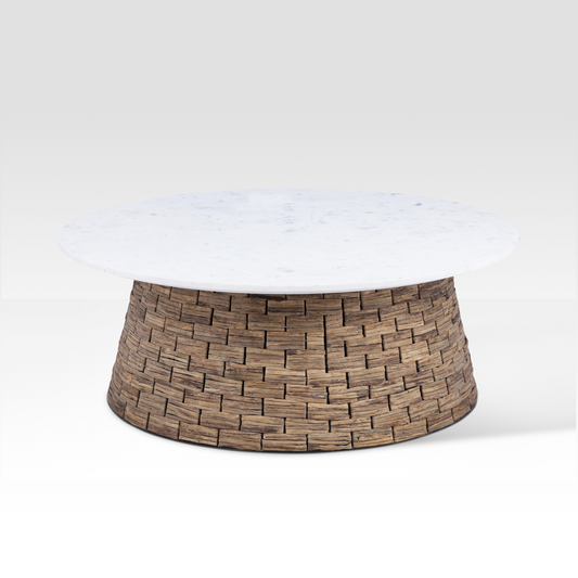 The Charme Coffee Table styled in a sunlit coastal living room, featuring a white marble top and a handwoven water hyacinth drum base.
