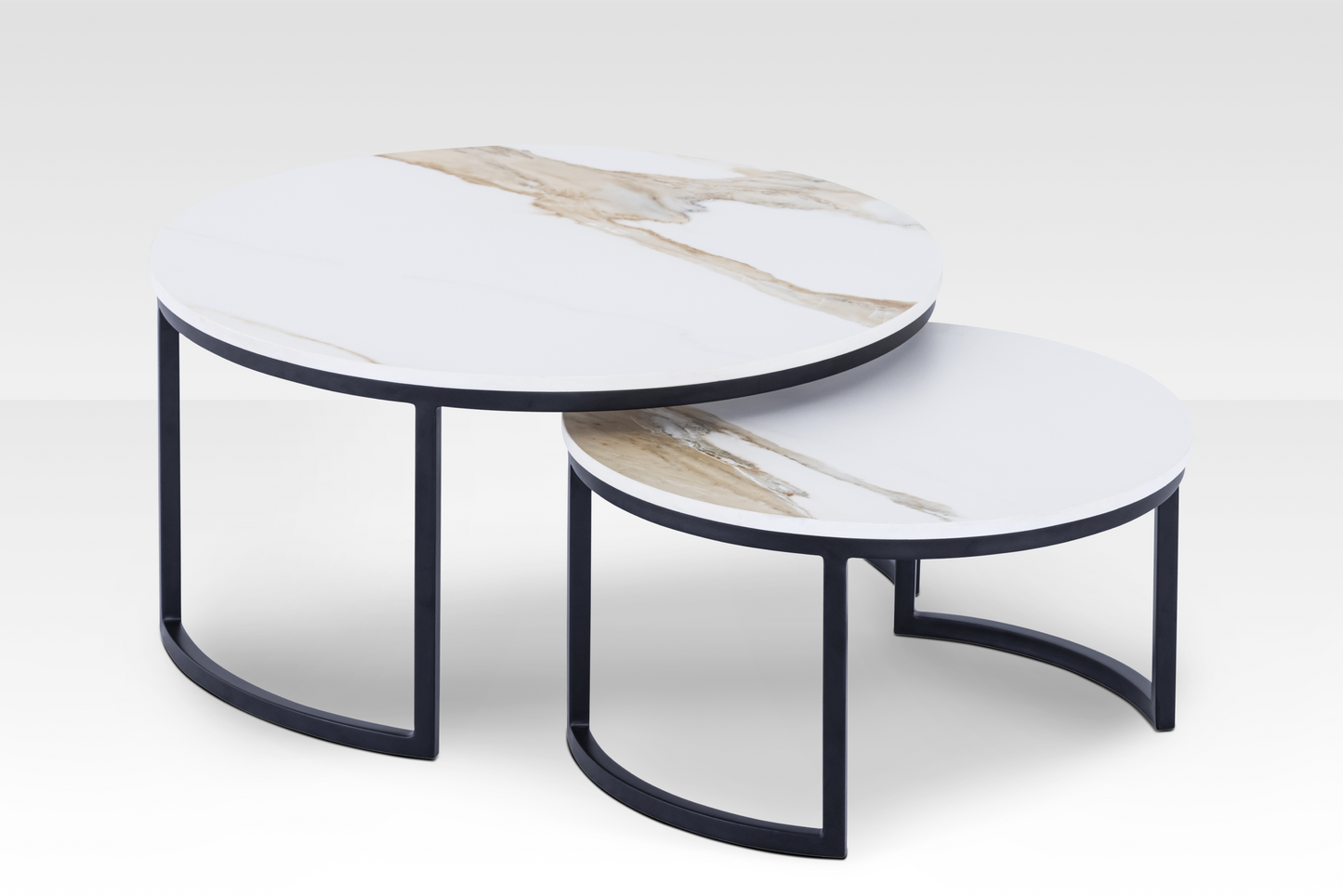 The Concord solid marble nesting tables in a black finish spread apart, highlighting the authentic stone veining and dynamic beveled edges.