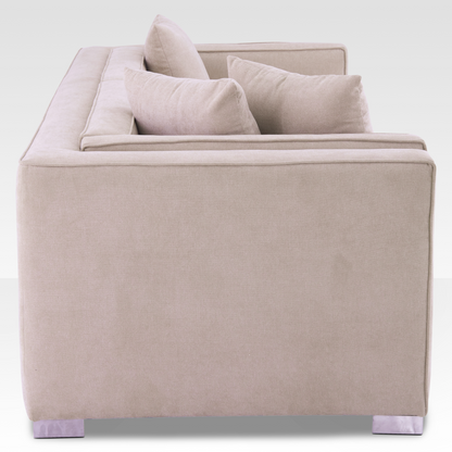 A side profile of the Elysian sofa highlighting the architectural inset track arm and warm sand-toned upholstery.