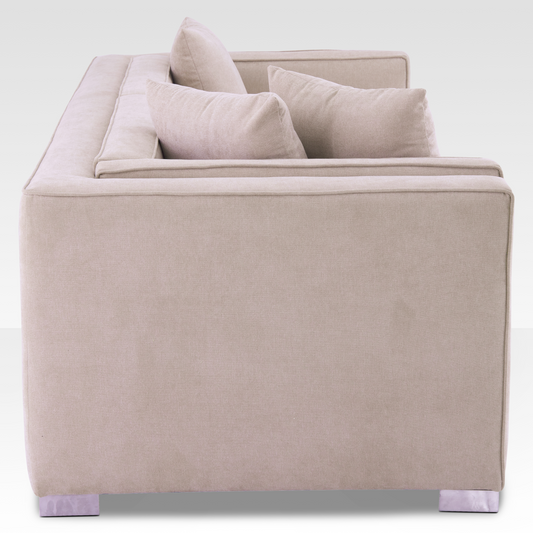 A side profile of the Elysian sofa highlighting the architectural inset track arm and warm sand-toned upholstery.