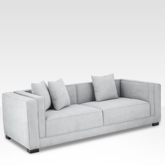 An angled view of the Elysian sofa in steel gray, highlighting the architectural inset arm and the dark steel foundation.