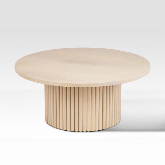 High-angle view of the Grove Coffee Table in a natural wood wash, featuring a circular top and a textured fluted drum base.