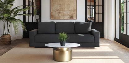 A modern living room featuring the Kyra pewter gray sofa paired with the Ray coffee table, which has a white marble top and a drum-style gold base.