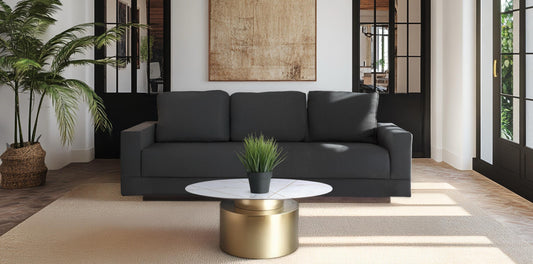 A modern living room featuring the Kyra pewter gray sofa paired with the Ray coffee table, which has a white marble top and a drum-style gold base.