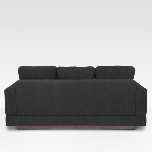 The rear view of the Kyra sofa, showcasing the continuous Pewter fabric wrap and the solid wood base at the floor.
