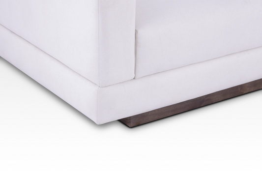 A focused close-up of the solid wood plinth base in a rich walnut finish on the Vanilla Cream Kyra sofa.