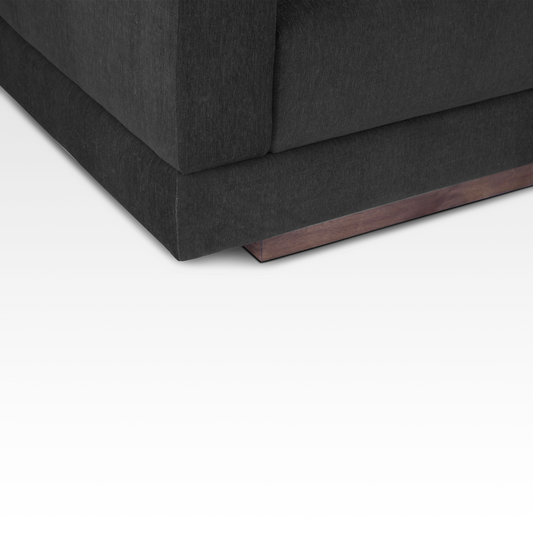 A close-up of the Kyra sofa's solid wood plinth base, emphasizing the natural wood grain and floating architectural look.
