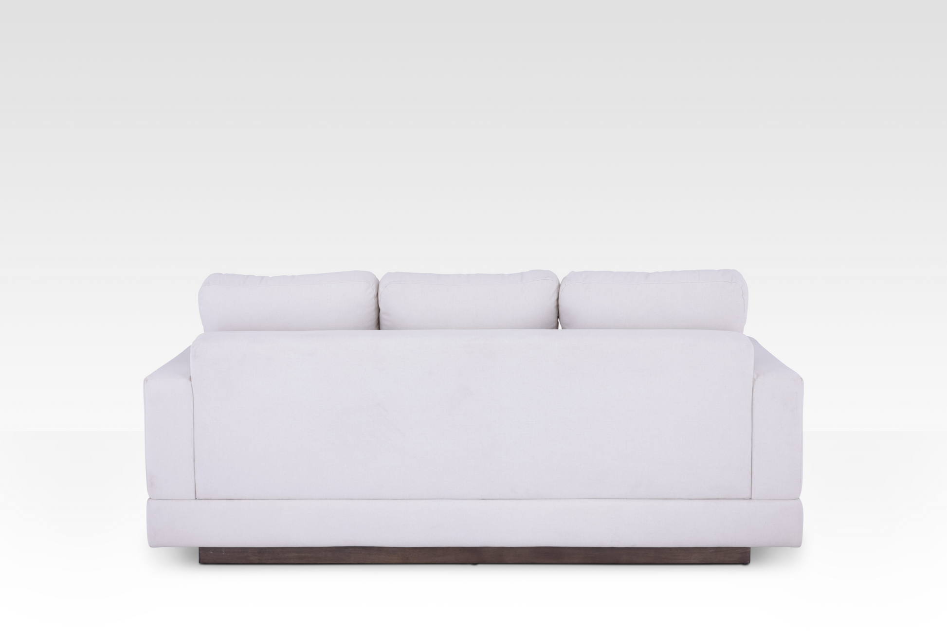 The clean rear view of the Kyra sofa, showing the continuous Vanilla Cream fabric wrap and the elegant solid wood base.