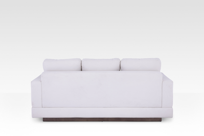 The clean rear view of the Kyra sofa, showing the continuous Vanilla Cream fabric wrap and the elegant solid wood base.