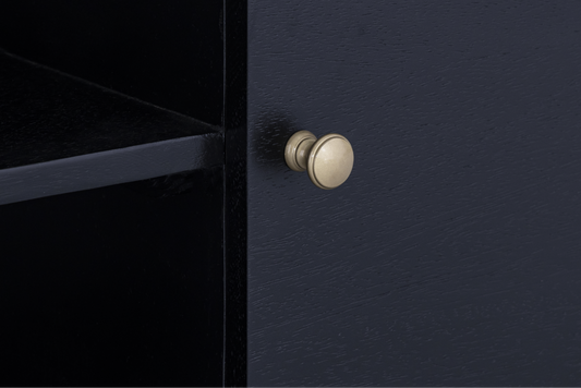 Close-up detail of the smooth curved wood grain and gleaming antique gold knob hardware on the Mira Sideboard.
