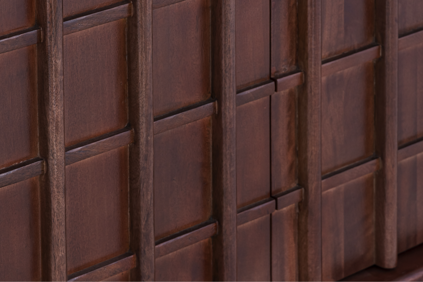 Macro shot of the geometric relief pattern and natural mango wood grain on the Quattro Sideboard door fronts.