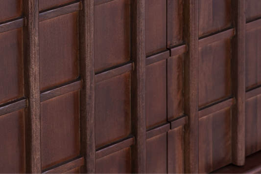 Macro shot of the geometric relief pattern and natural mango wood grain on the Quattro Sideboard door fronts.