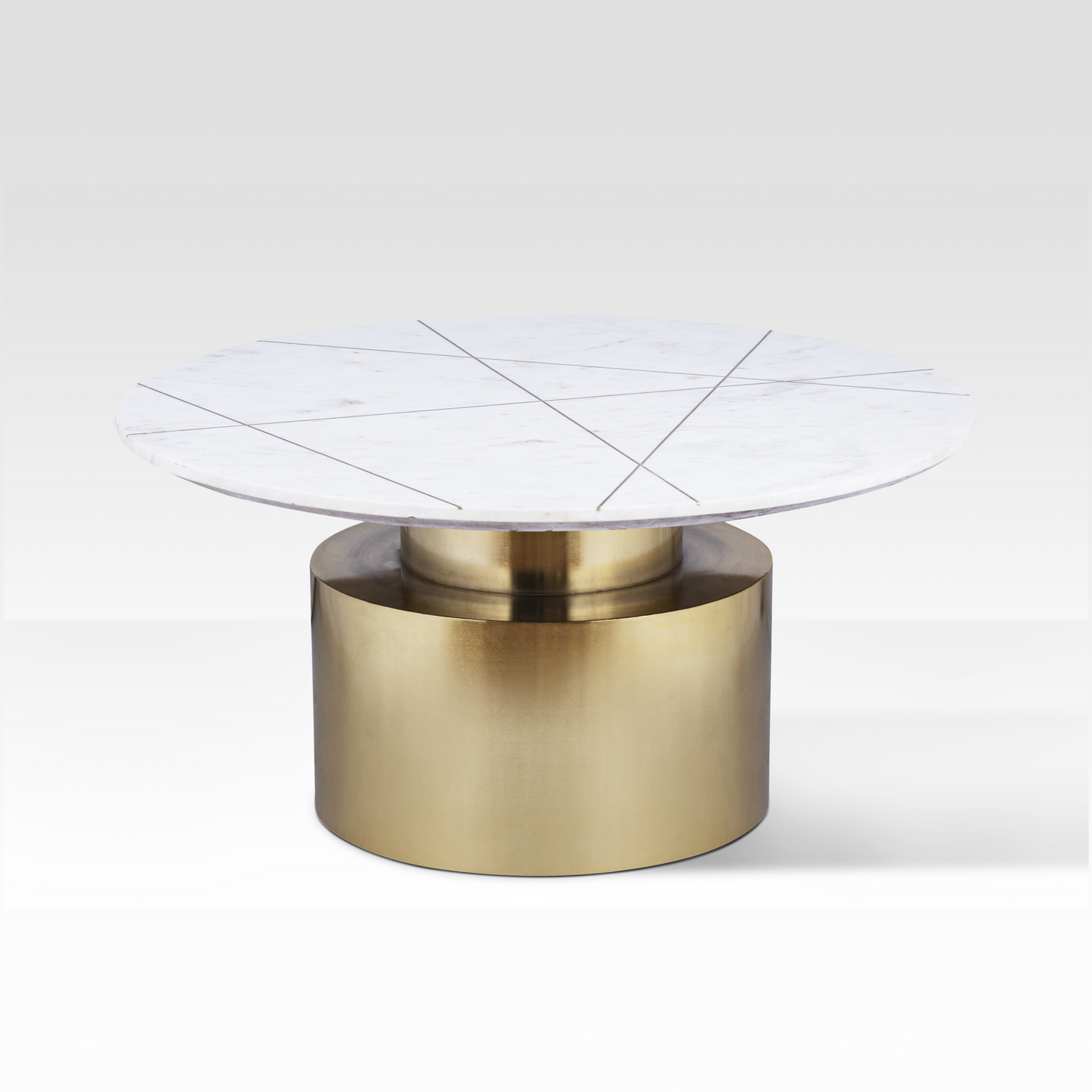 An angled view of the Ray Coffee Table featuring a white marble top with geometric brass inlay lines and a stepped brass pedestal base.