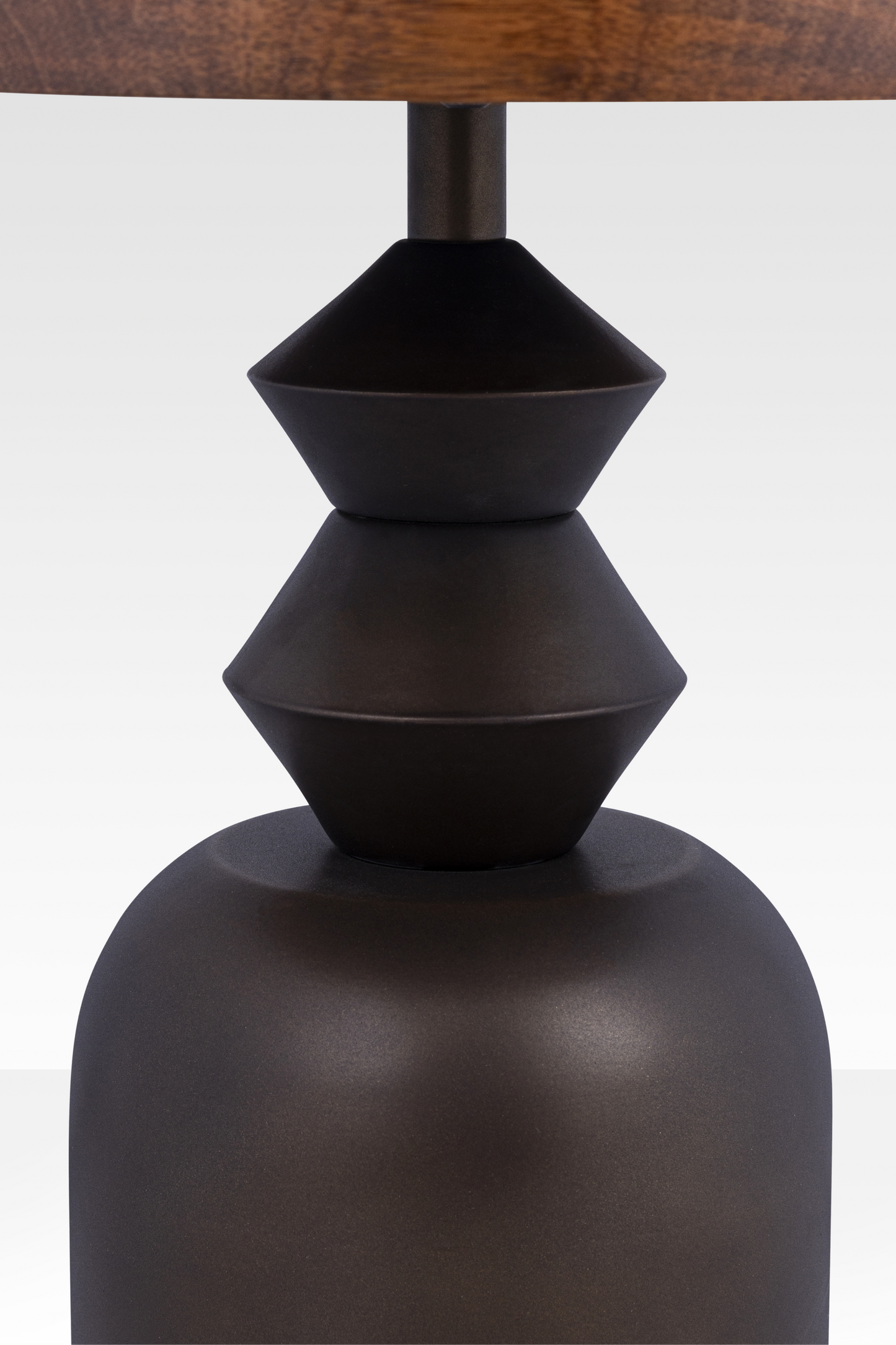 A close-up of the Zentri table’s dark bronze metal base, emphasizing the hand-cast texture and sharp geometric conical joints.