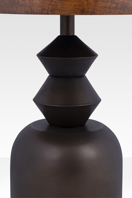 A close-up of the Zentri table’s dark bronze metal base, emphasizing the hand-cast texture and sharp geometric conical joints.