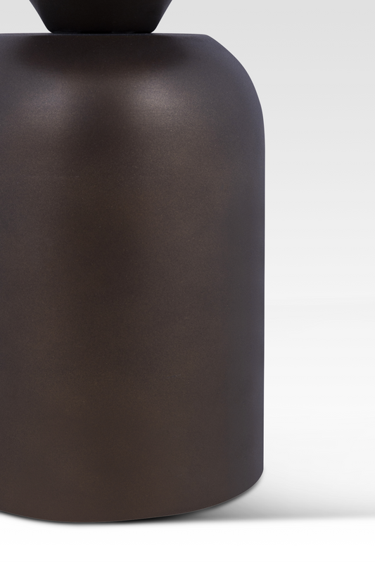 A macro view of the Zentri table’s rounded metal base, showcasing the durable matte dark bronze finish and substantial industrial weight.